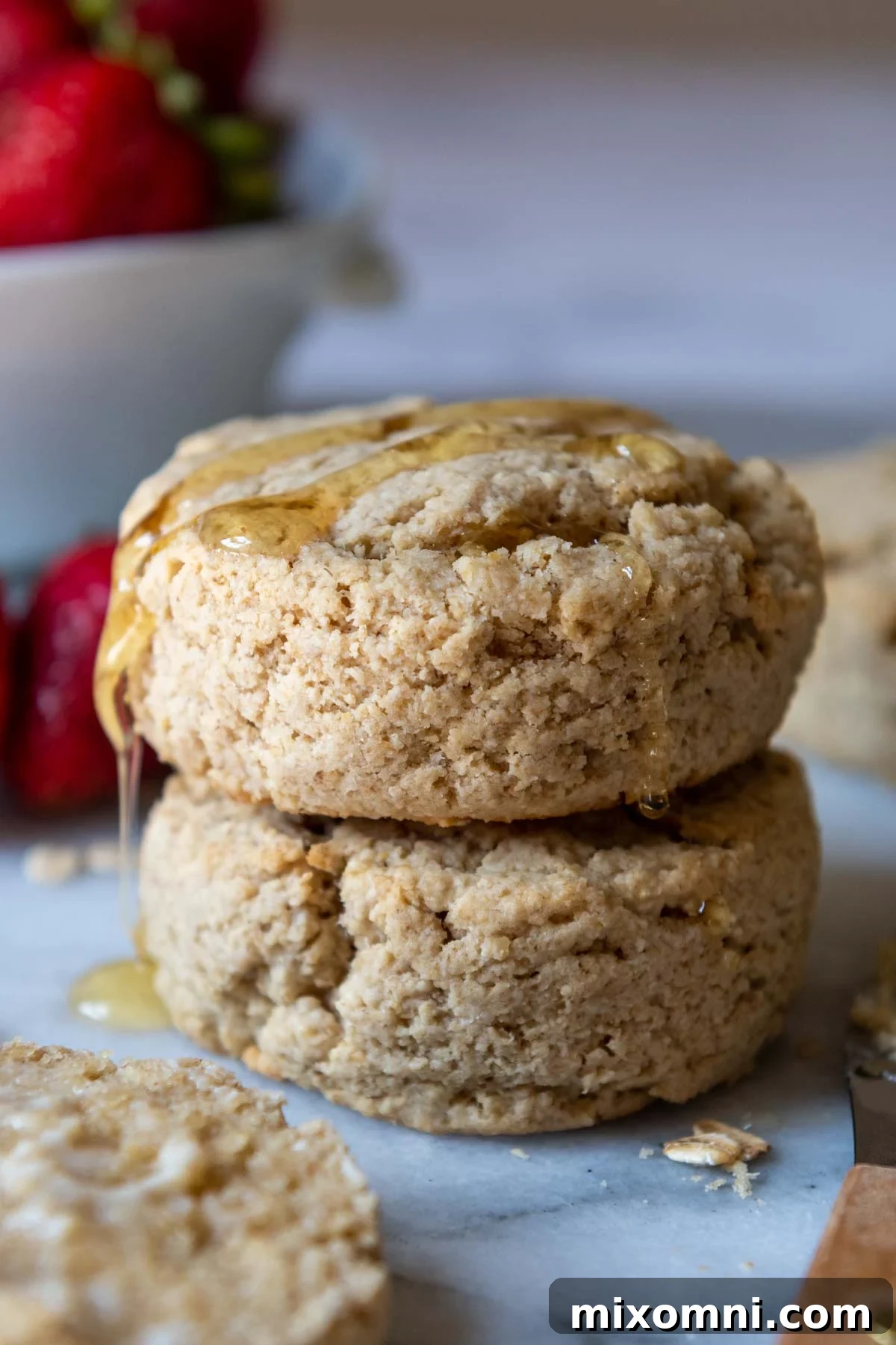 a stack of 2 biscuits with honey dripping over the top.