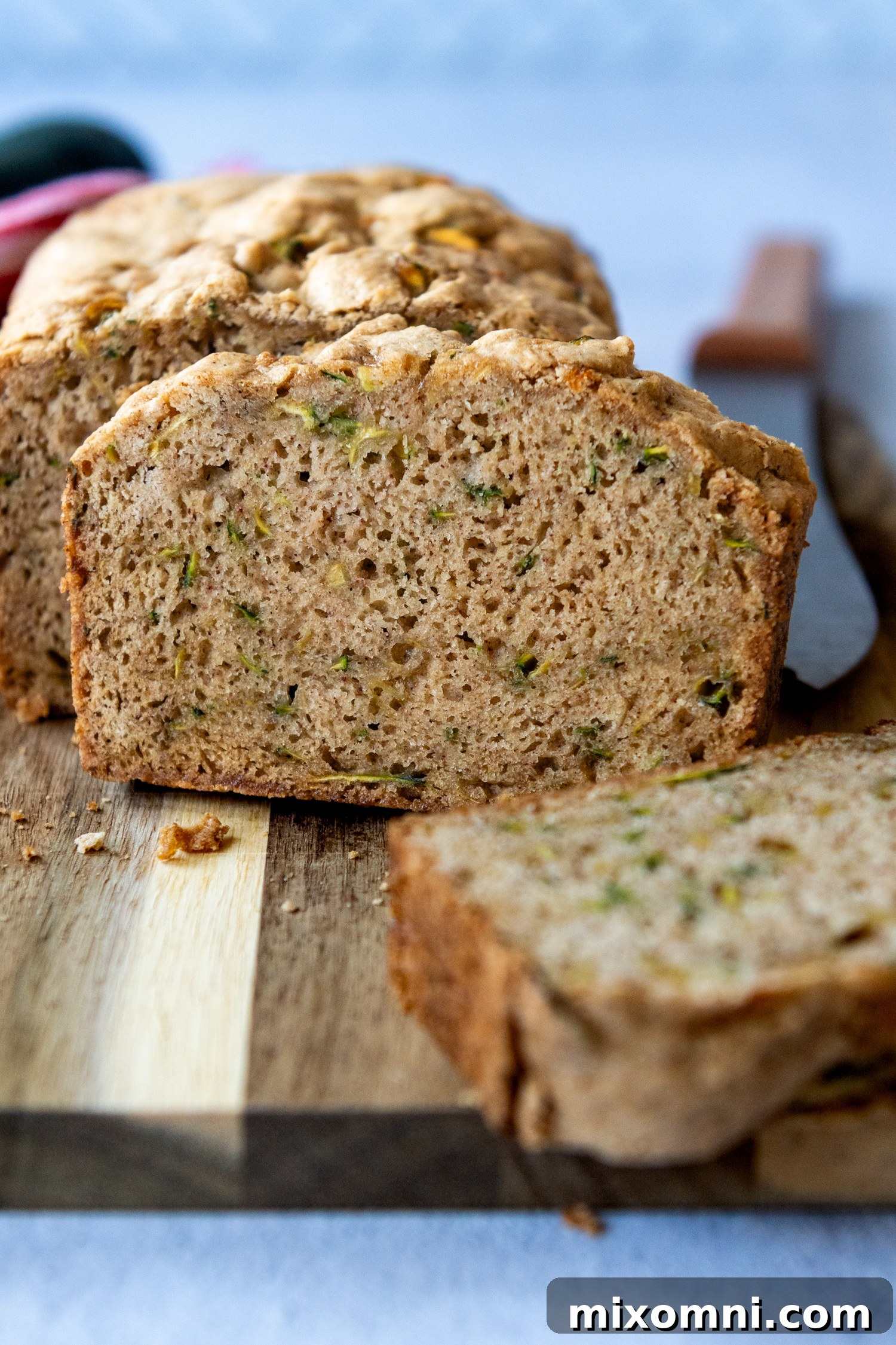 A perfectly baked slice of gluten-free zucchini bread positioned straight on a wooden cutting board.