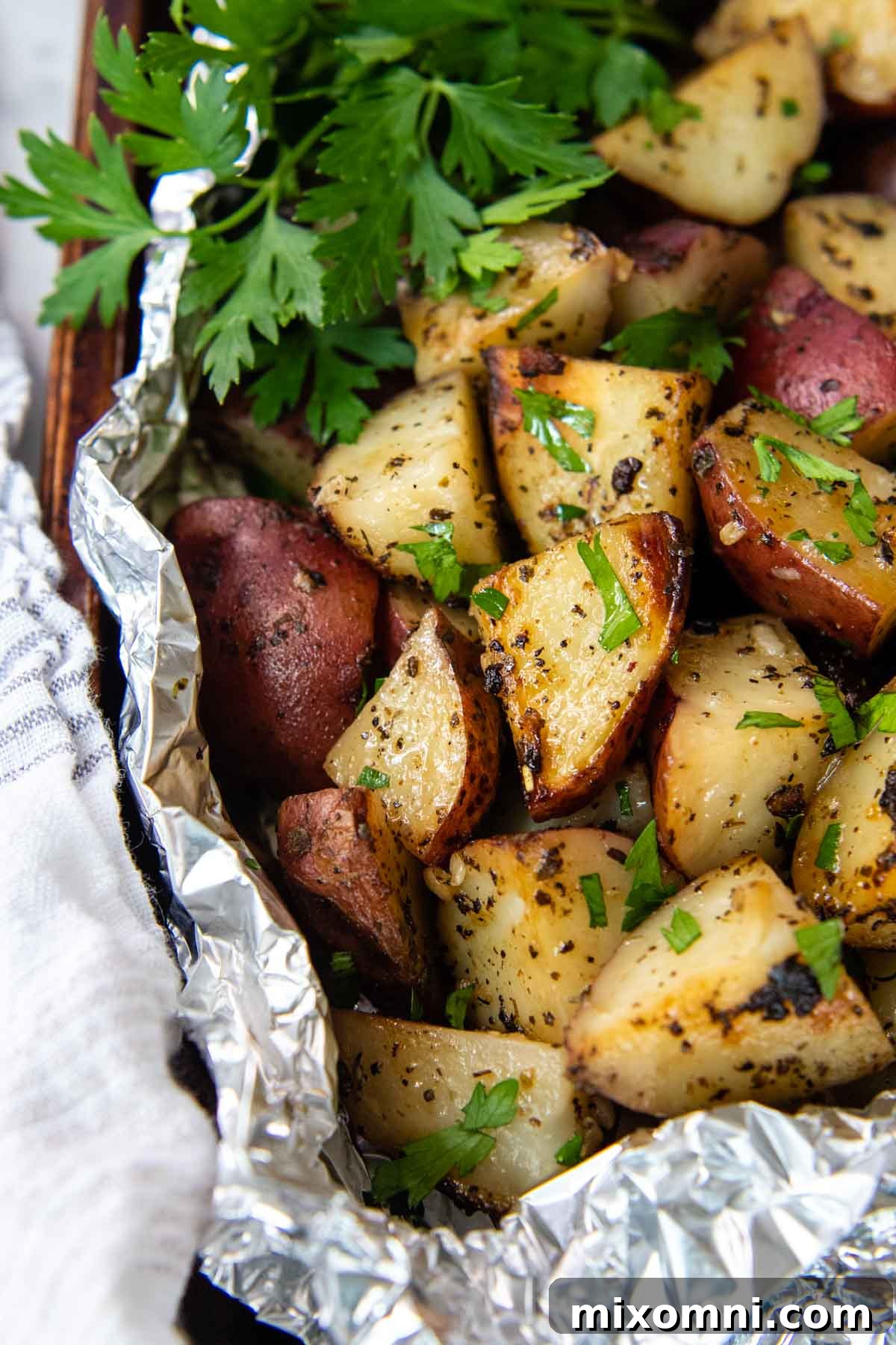 Grilled red potatoes cooked in foil packets, garnished with fresh parsley, ready to be served as a simple weeknight side.
