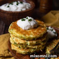 Stack of crispy gluten-free zucchini fritters on a wooden plate.