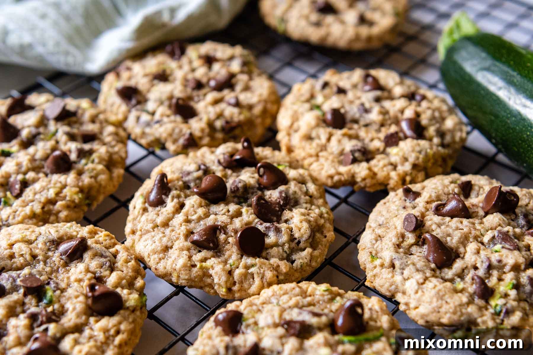Freshly baked gluten-free zucchini cookies cooling on a wire rack, with a whole zucchini resting beside them, ready to be enjoyed.