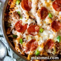 close up of baked pasta skillet with a spoon and linen laying next to it.