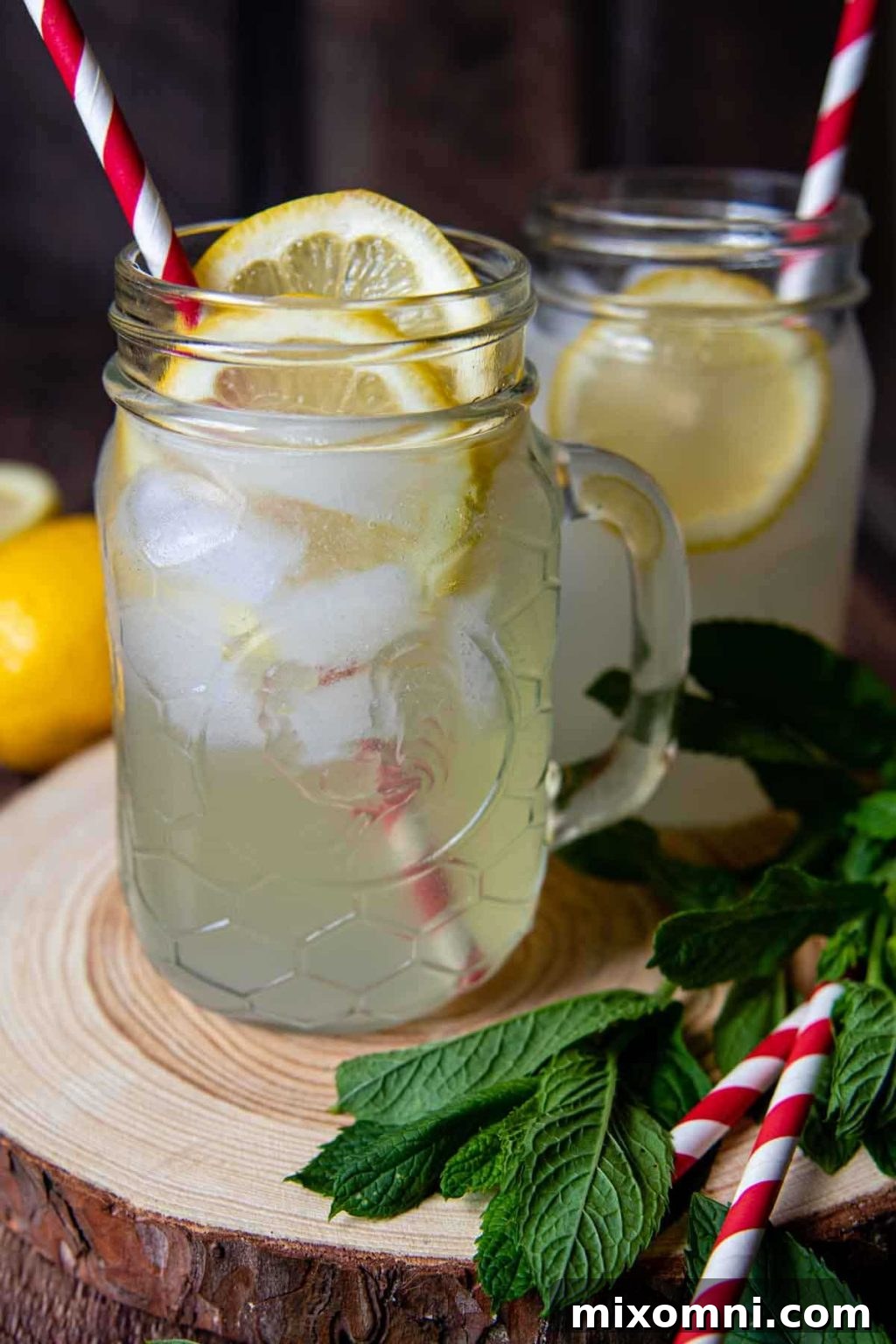 A refreshing Spiked Lemon Shake-Up Cocktail served in a classic mason jar, garnished with red and white straws, resting on a wooden coaster.