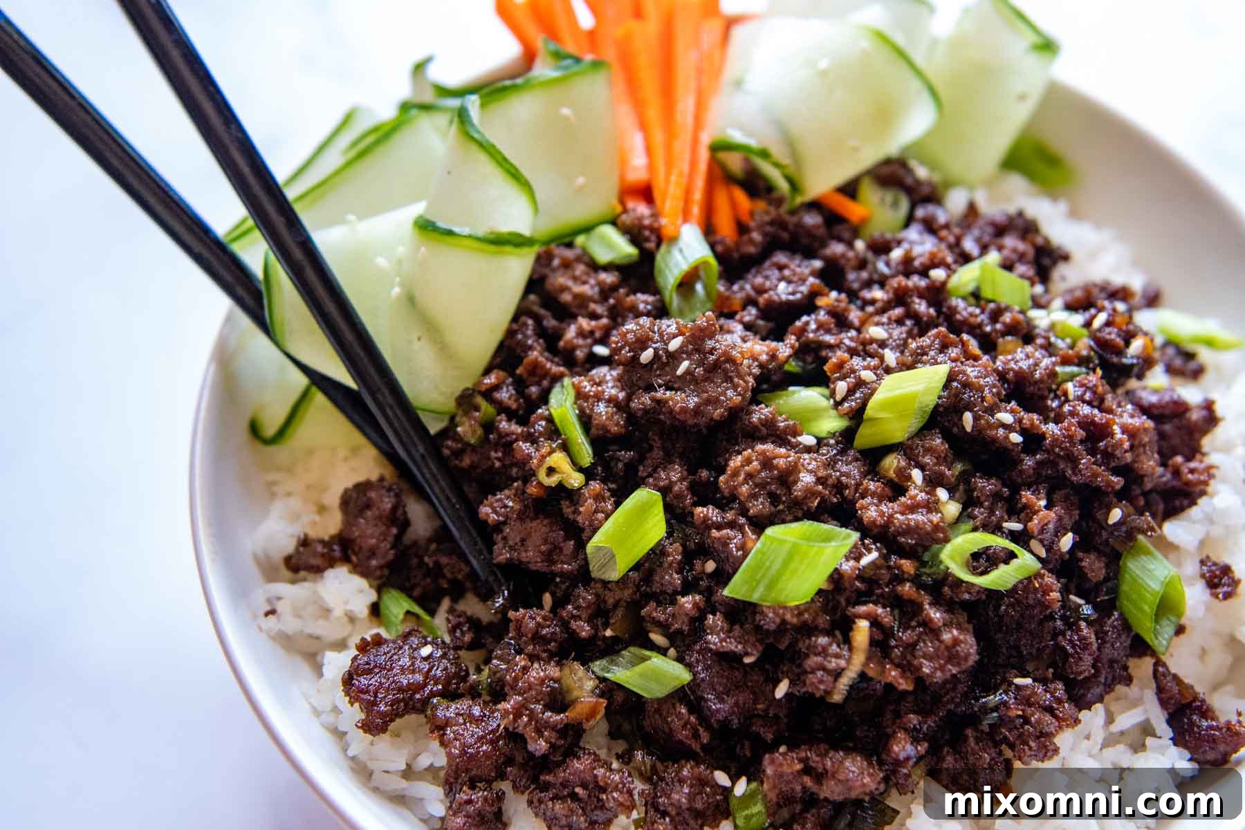 A close-up shot of a bulgogi bowl adorned with various garnishes, presented appealingly with chopsticks resting on the side, highlighting the dish's texture and inviting appeal.