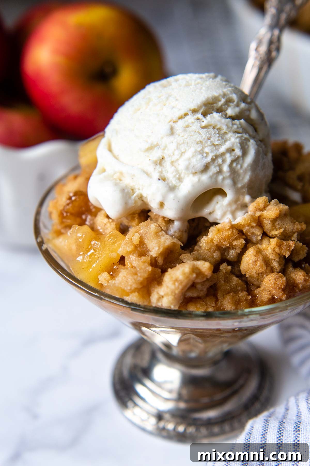 A serving of perfectly baked gluten-free apple crisp topped with a scoop of melting vanilla ice cream, showcasing the golden streusel and tender apple filling.
