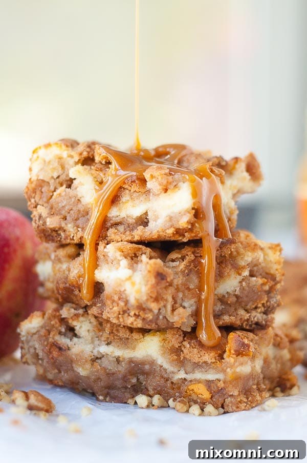 a stack of apple cheesecake bars with caramel dripping over