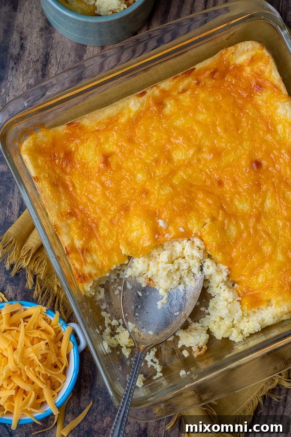 An overhead shot of a cheesy grits casserole, with shredded cheese scattered nearby.