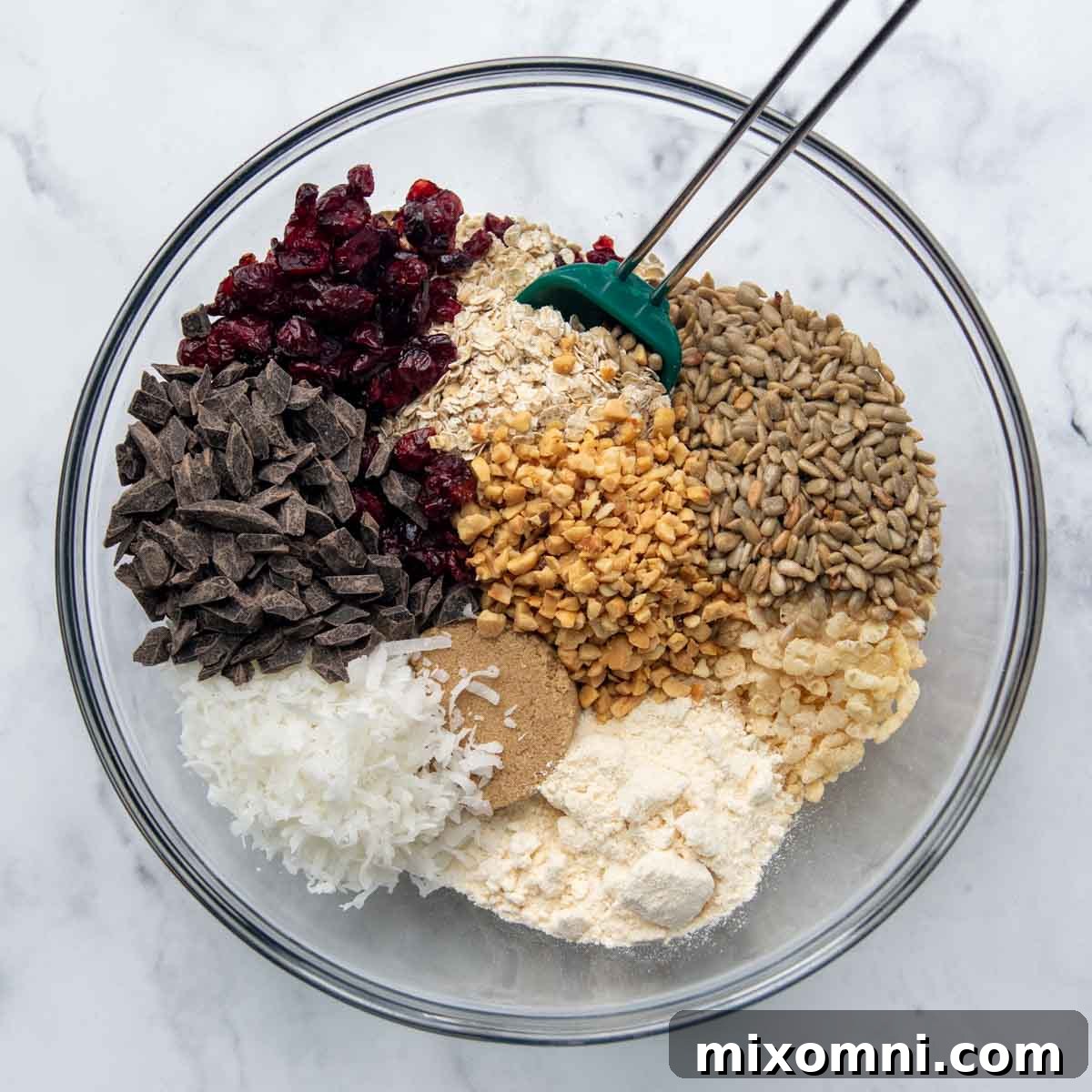 The dry ingredients for gluten-free granola bars, including oats, rice cereal, nuts, coconut, cranberries, and chocolate chips, thoroughly mixed together in a large bowl.