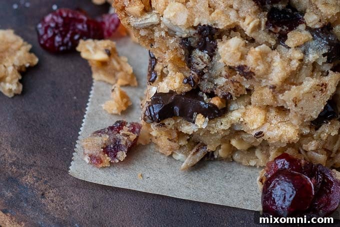 Close-up of a homemade gluten-free chocolate chip granola bar with a bite taken out, revealing gooey melted chocolate and a chewy texture.