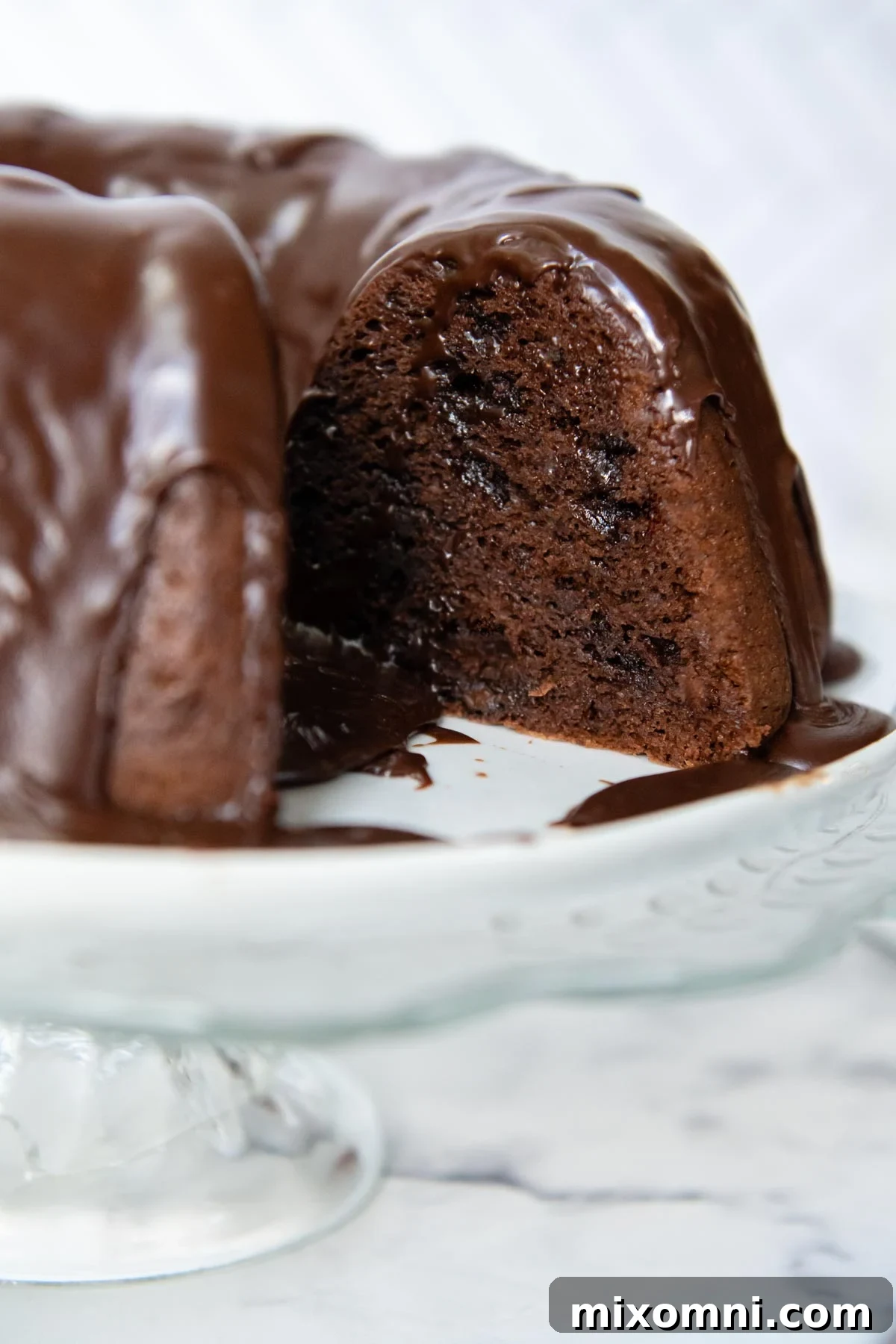 A beautifully decorated gluten-free chocolate bundt cake, sliced to reveal its moist interior.