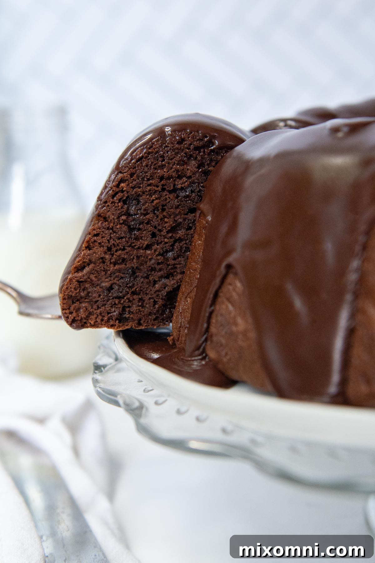 A slice of gluten-free chocolate bundt cake being lifted from a platter, showcasing its rich texture.