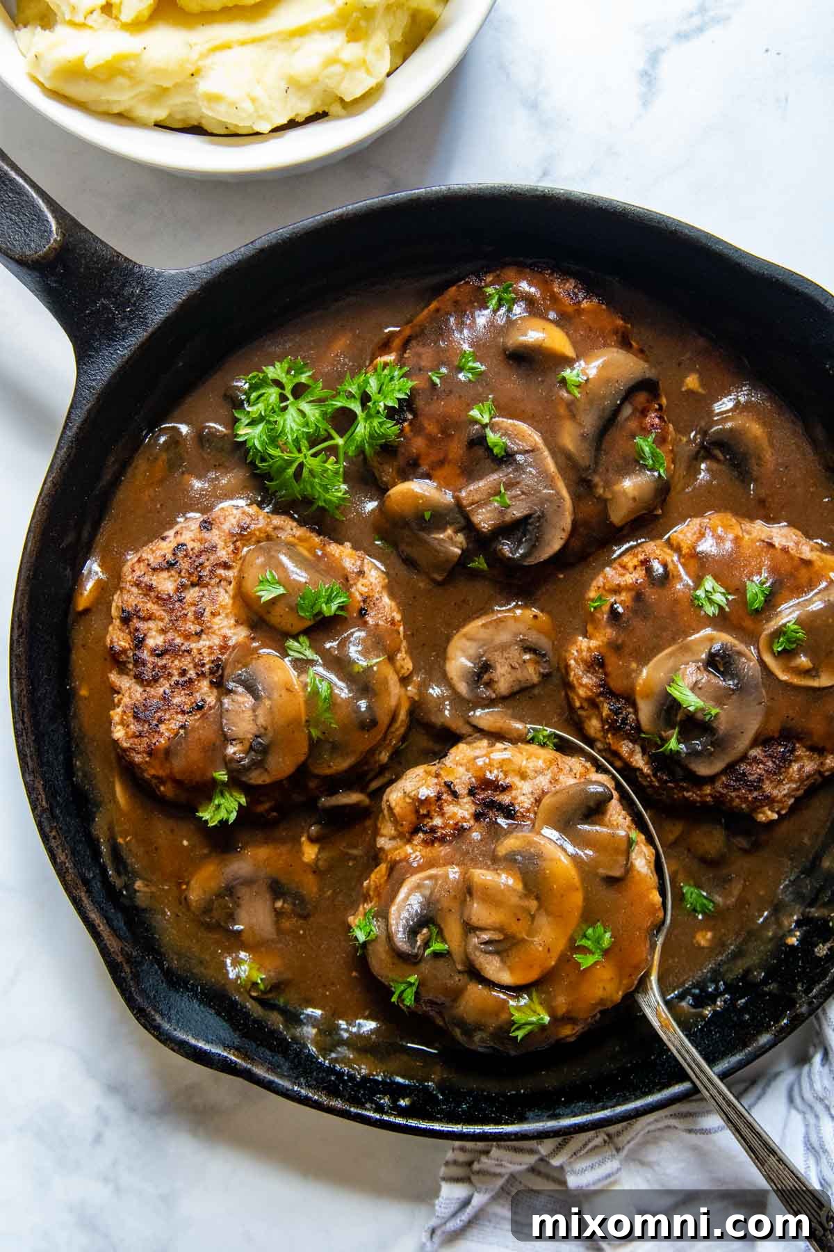Cooked Salisbury steaks with mushroom gravy, perfectly nestled in a cast iron skillet, ready to be served.