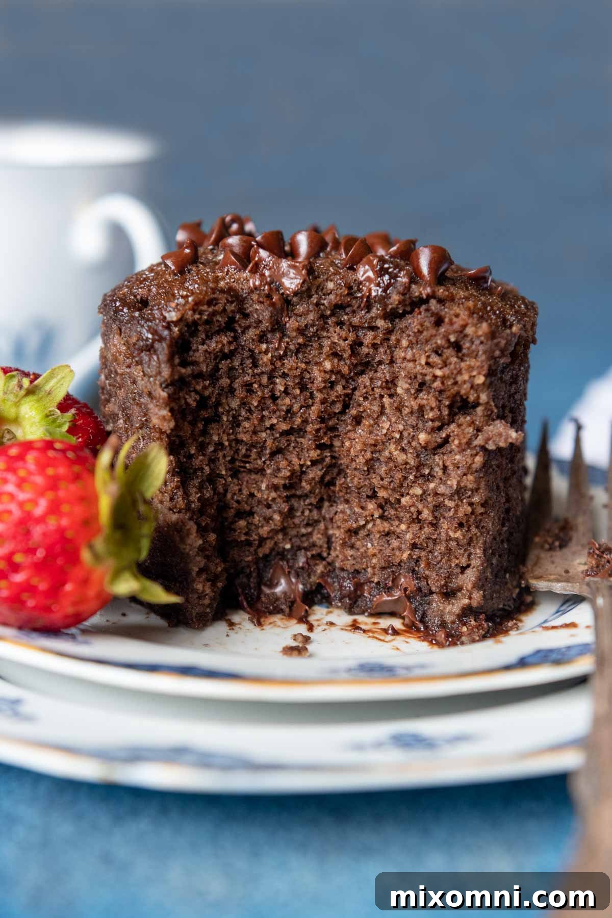 A perfectly baked chocolate almond flour mug cake with a bite taken out, revealing its moist and fudgy interior. It's ready to be enjoyed as a quick, gluten-free, and dairy-free dessert.