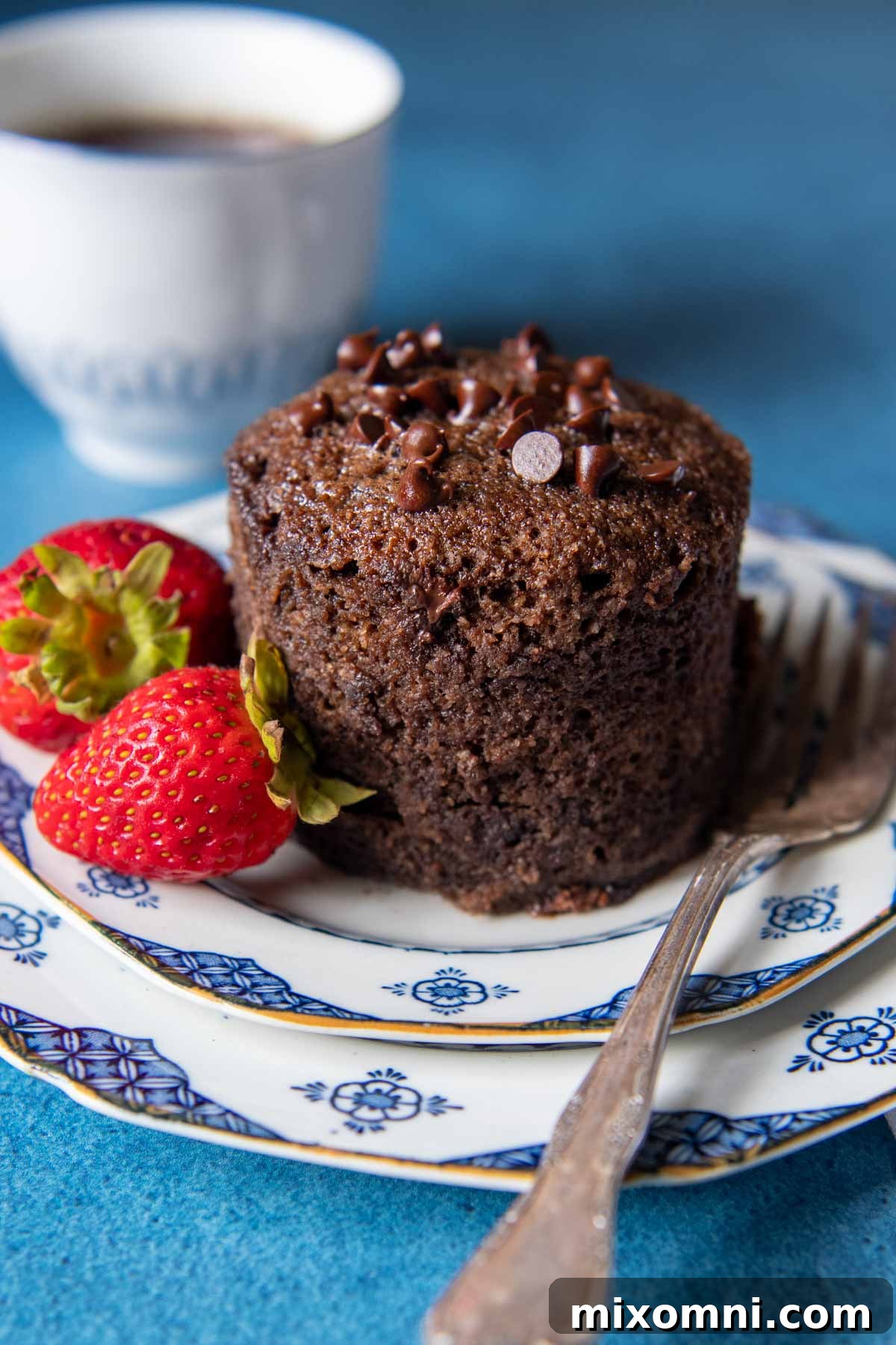 A freshly baked almond flour mug cake, inverted out of its mug and placed elegantly on a plate, with a fork resting beside it, inviting a delicious bite.
