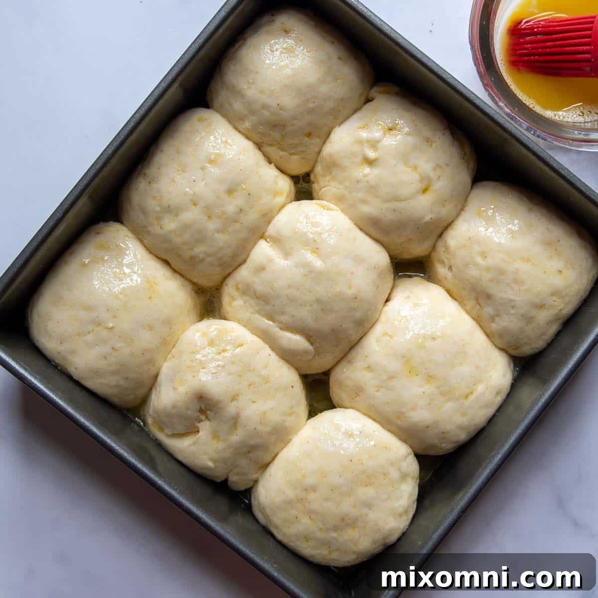 Gluten-free dinner rolls in a baking pan, showing their increased volume after rising.
