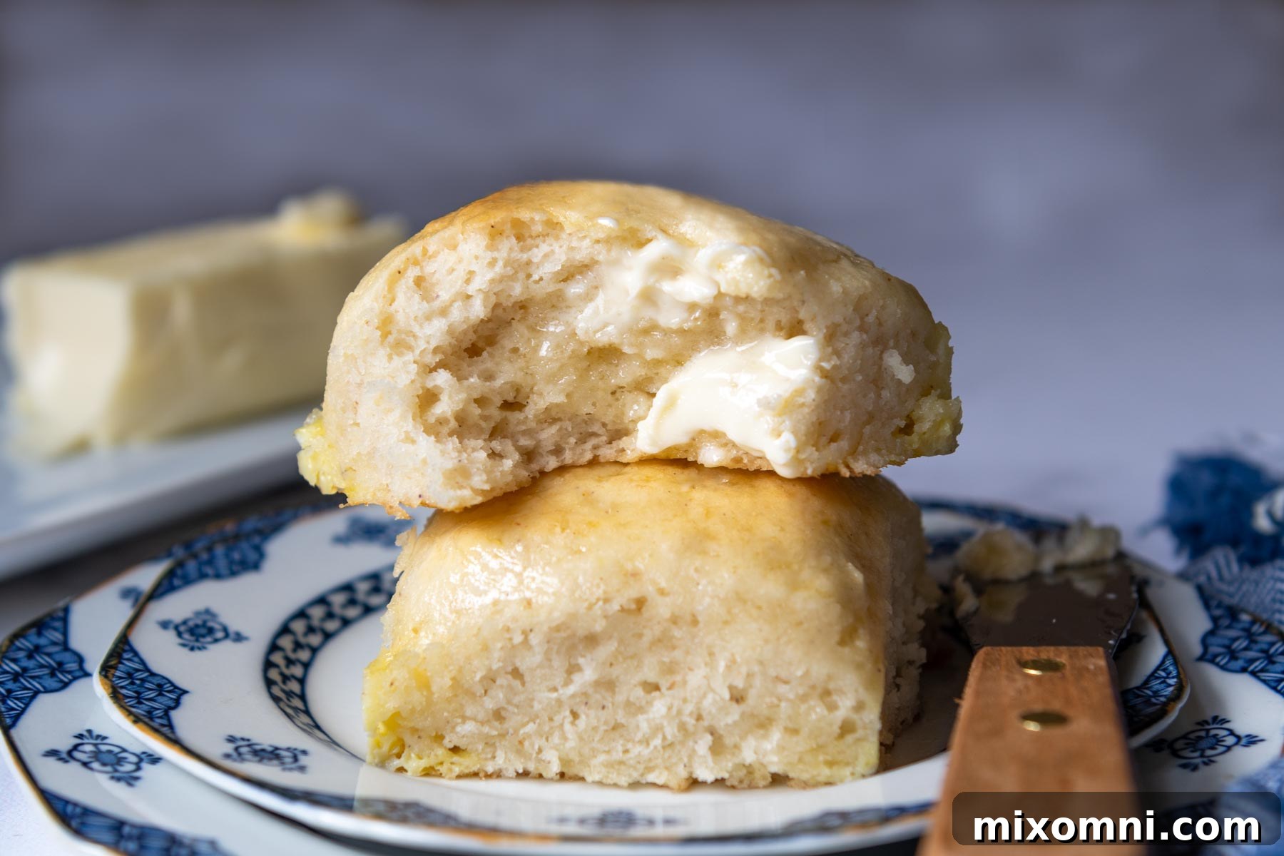 Two soft gluten-free rolls stacked, glistening with melted butter.