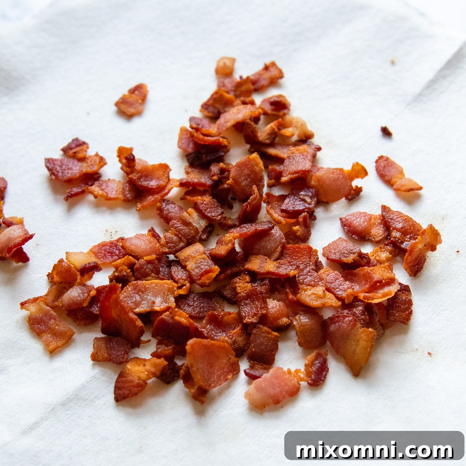 Crispy bacon strips resting on a paper towel-lined plate to absorb excess grease, ready to be added back to the chowder later.