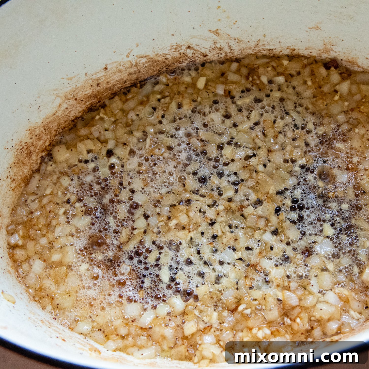 Diced onions gently cooking and caramelizing in the flavorful bacon grease and butter in a large pot, creating an aromatic base for the chowder.