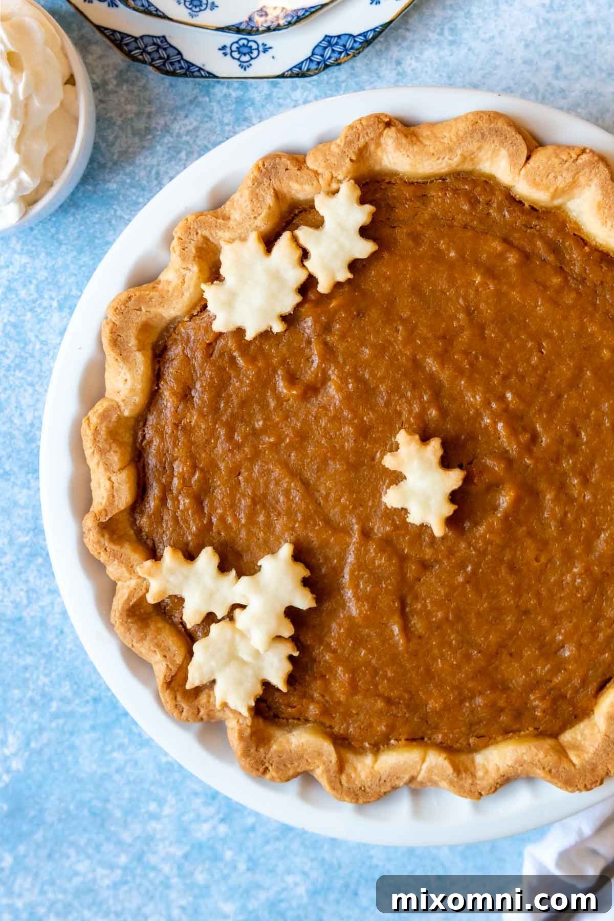 Overhead shot of a golden-brown sweet potato pie on a rustic blue background, elegantly presented and ready to be served for a festive occasion.
