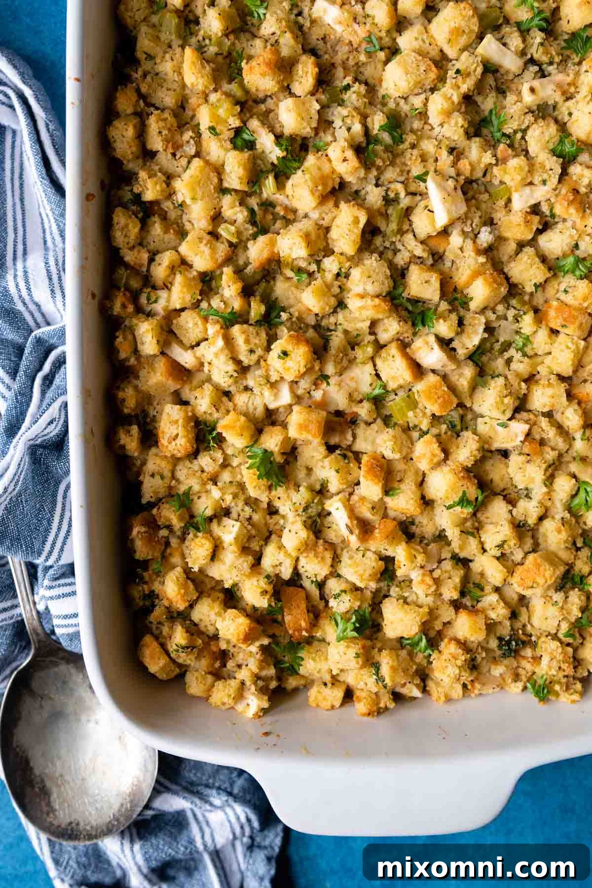 overhead shot of stuffing in a white dish with an antique spoon next to it.