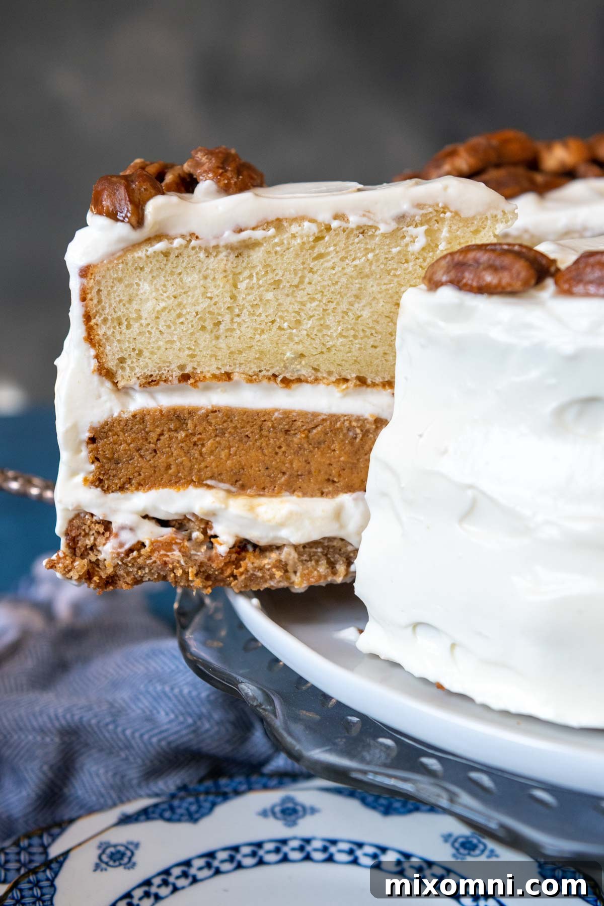 a slice of pumpkin pie layer cake coming out from cake platter.