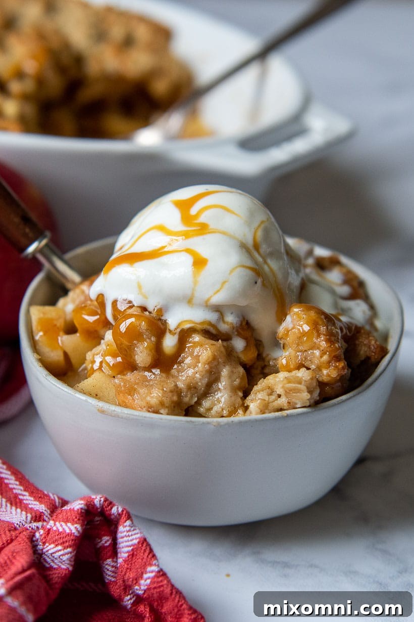 a bowl of apple crisp with ice cream and caramel on top
