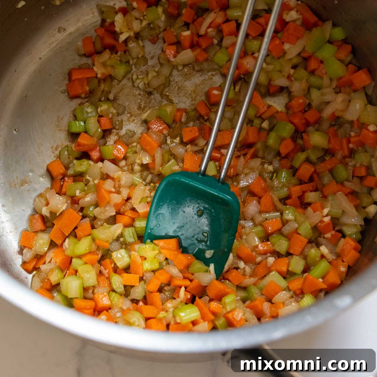 Freshly diced onions, celery, and carrots sautéing in a large soup pot with savory bacon drippings, creating the aromatic base for the soup.