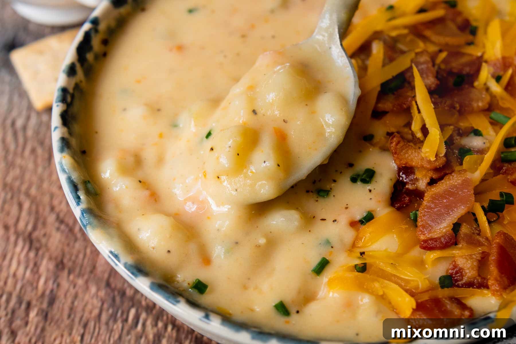 A close-up shot of a spoon lifting a perfect bite of thick, creamy potato soup, showcasing its rich texture and chunks of potato.
