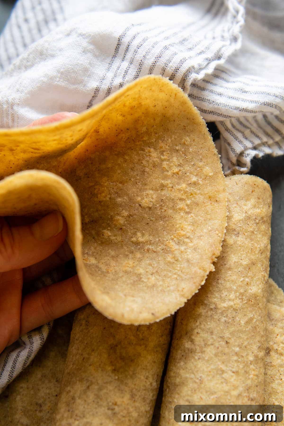 An almond flour tortilla being held up to demonstrate its exceptional flexibility.