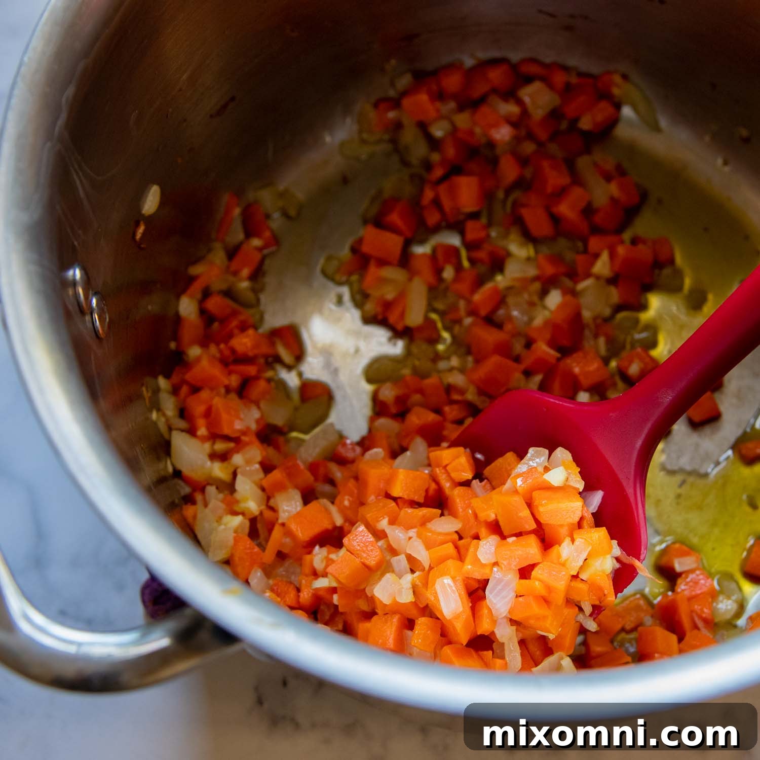 The diced onions and carrots cooking in a pot, softening in butter.