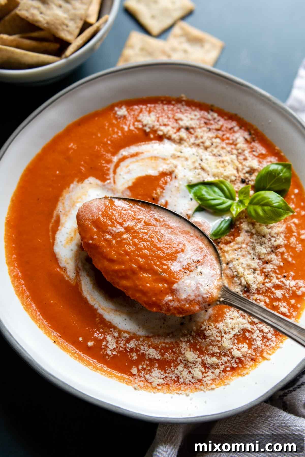 A spoon lifting out of a bowl of creamy gluten-free tomato soup, showing its rich texture.