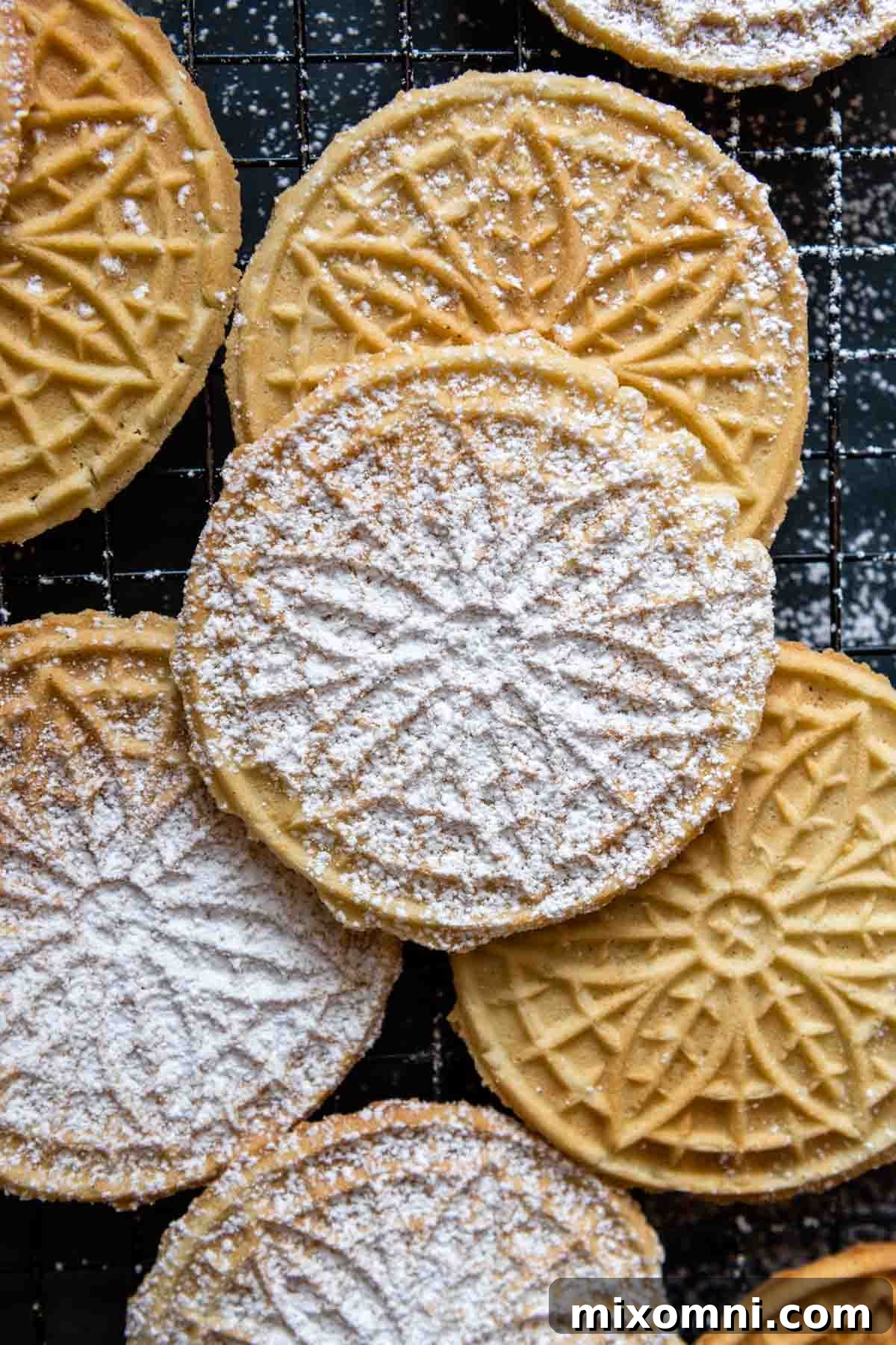 An overhead shot showcasing beautifully arranged gluten-free pizzelles, lightly dusted with powdered sugar, cooling on a wire rack.