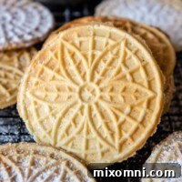 A crisp gluten-free pizzelle leaning against a stack, surrounded by others.