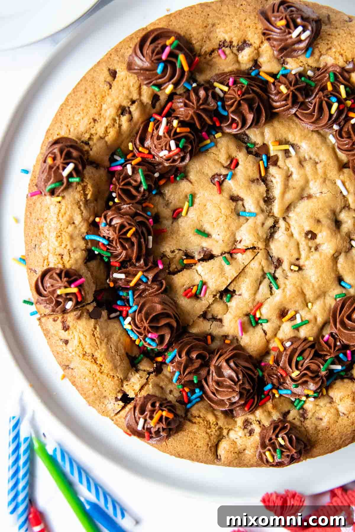 Overhead shot of a festive gluten-free cookie cake, richly frosted and adorned with colorful sprinkles, ready for a celebration.