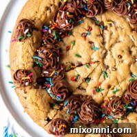 overhead shot of gluten free cookie cake with sprinkles and frosting on top.