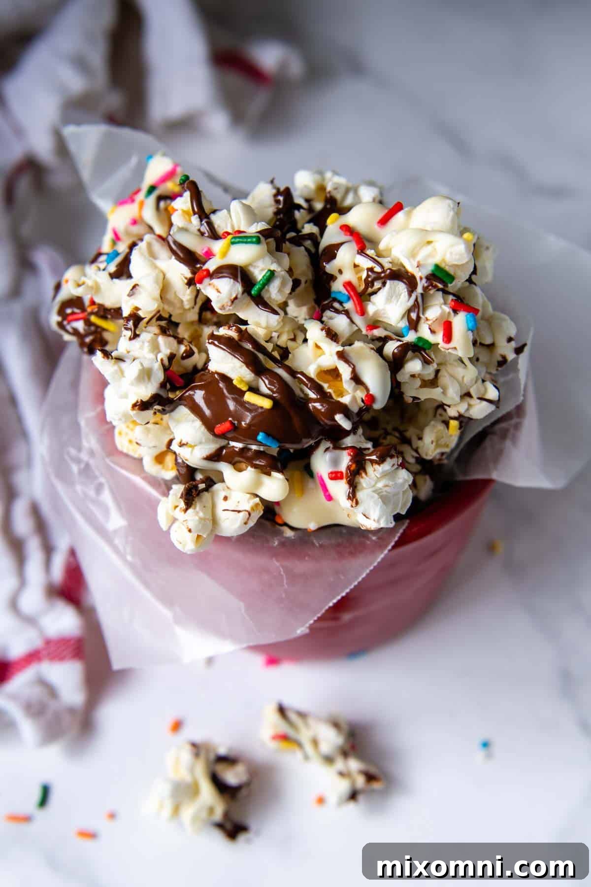Overhead shot of chocolate popcorn in a vibrant red decorative container, perfect for holiday gifting.