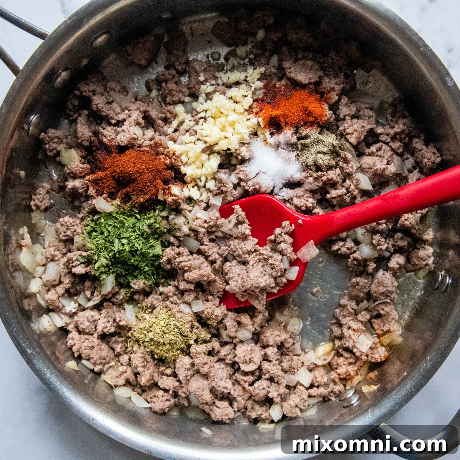 The ground beef and onion mixture simmering with seasonings in a skillet, forming the base of the shepherd's pie.