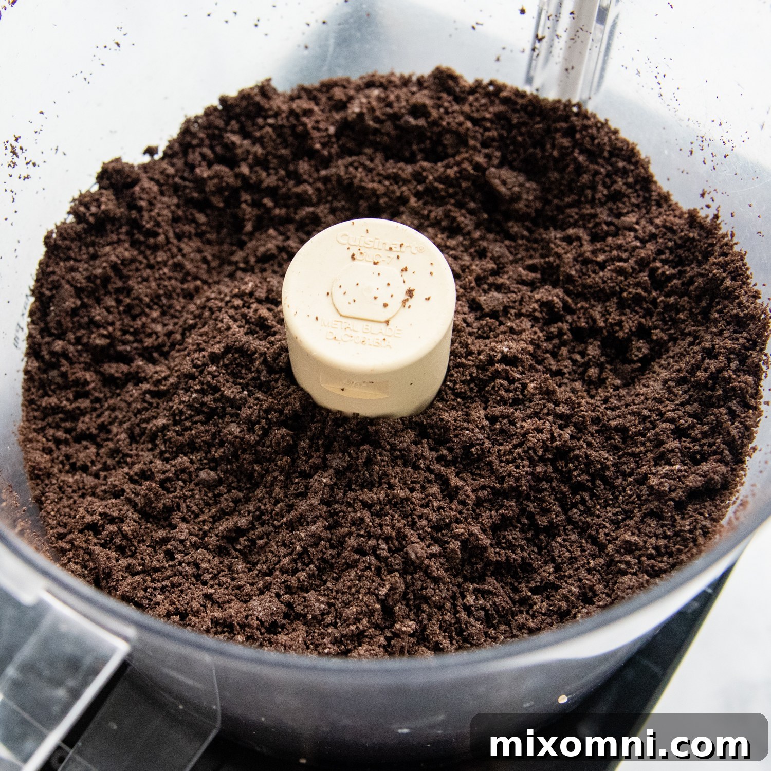 Gluten-free Oreos being crushed into fine crumbs in a food processor, forming the base for delicious truffles.