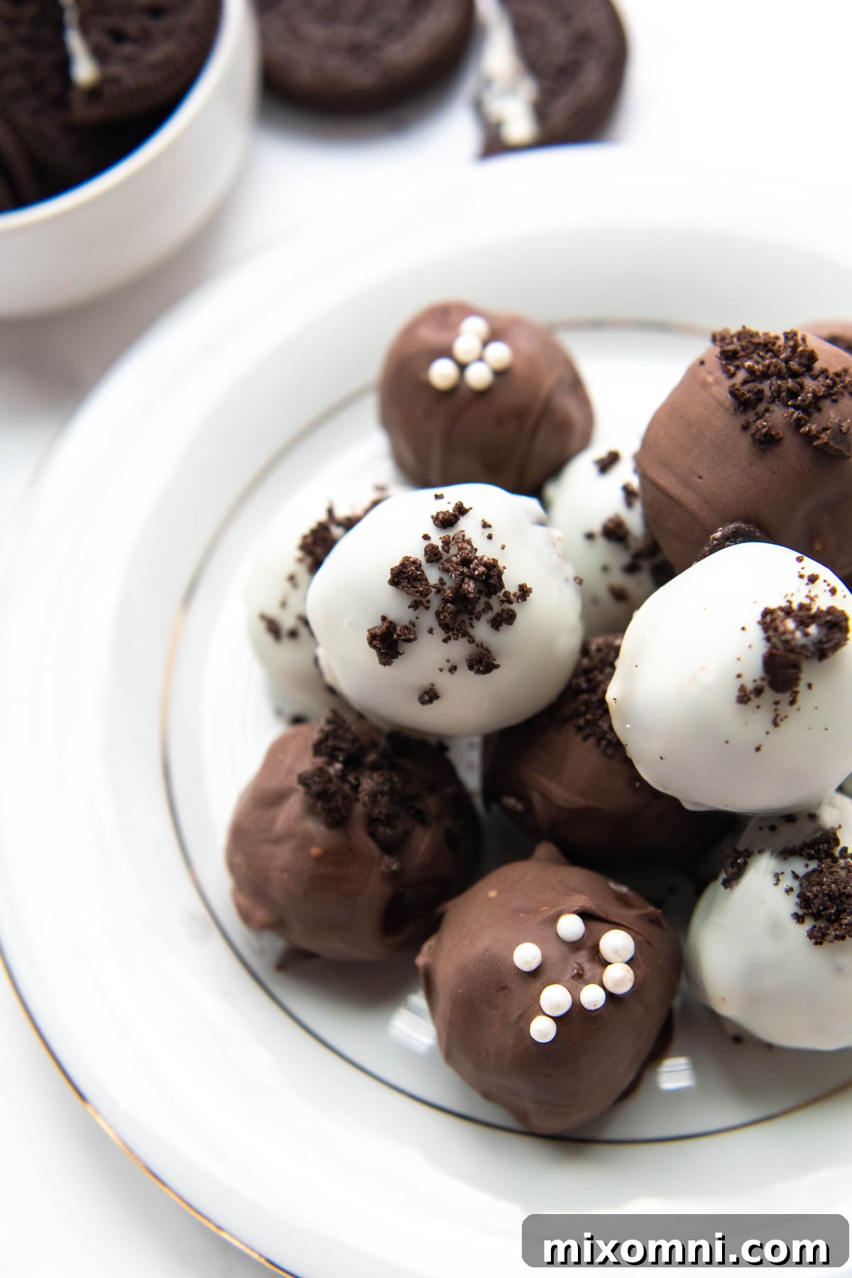 A minimalist plate featuring a collection of elegant black and white gluten-free truffles against a crisp white background, emphasizing their classic appeal.