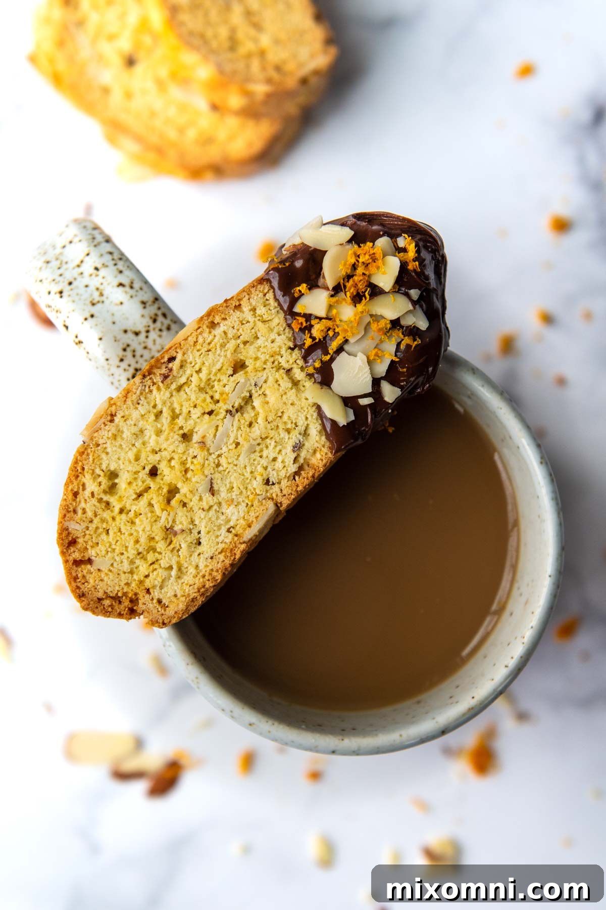 a gluten-free biscotti dipped in chocolate resting on top of a coffee cup