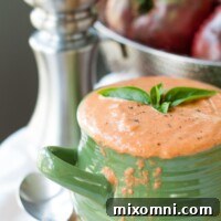 A bowl of creamy roasted tomato soup with fresh basil on top.