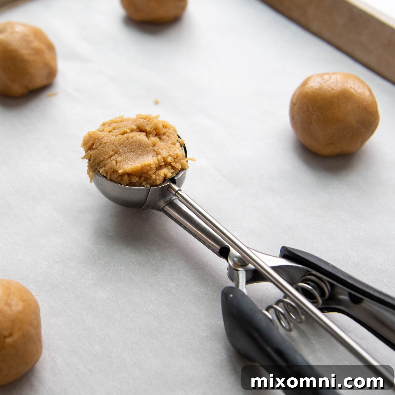 A medium cookie scoop filled with dough, ready to be placed on a baking sheet.