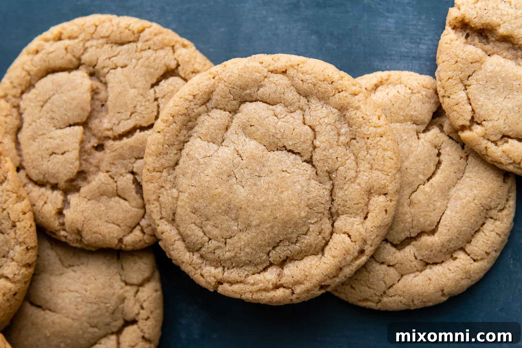 A row of perfectly baked gluten-free peanut butter cookies lined up on a blue background.