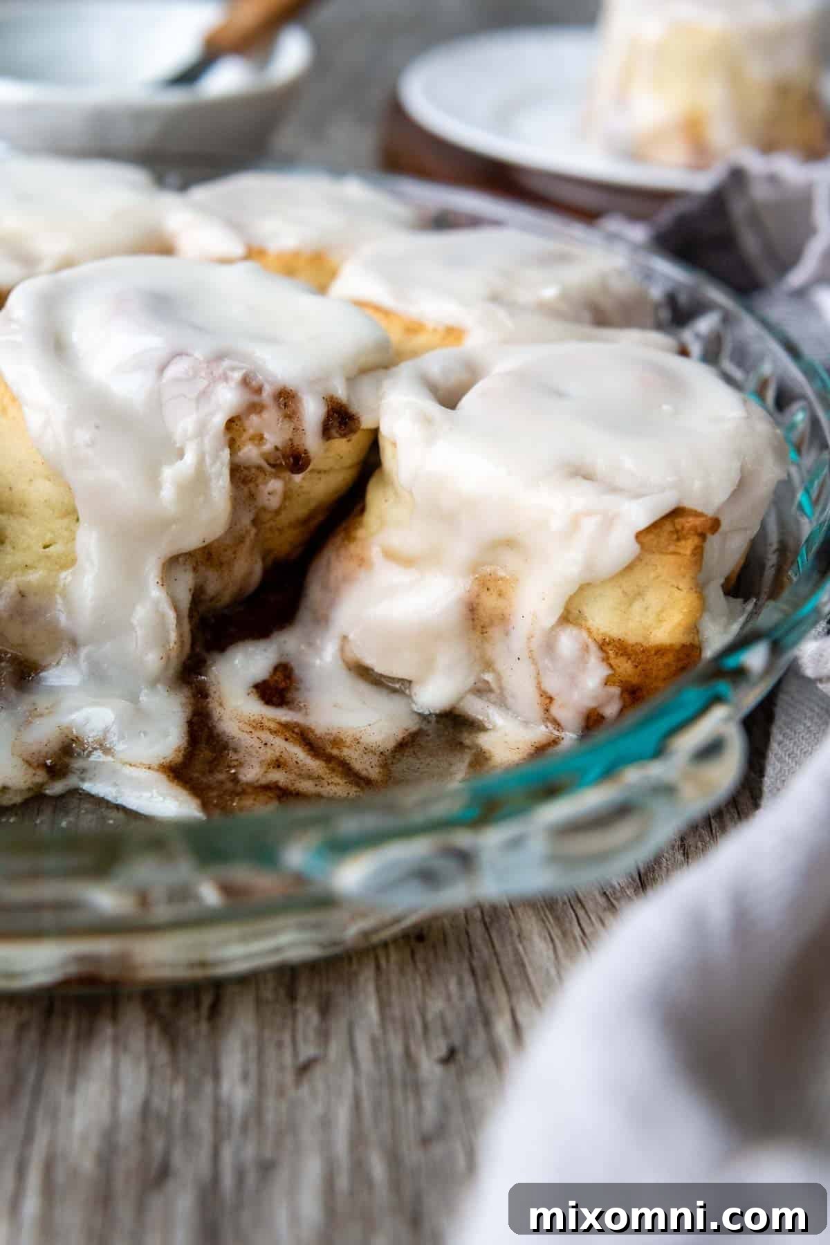 frosted cinnamon rolls in a glass pan.