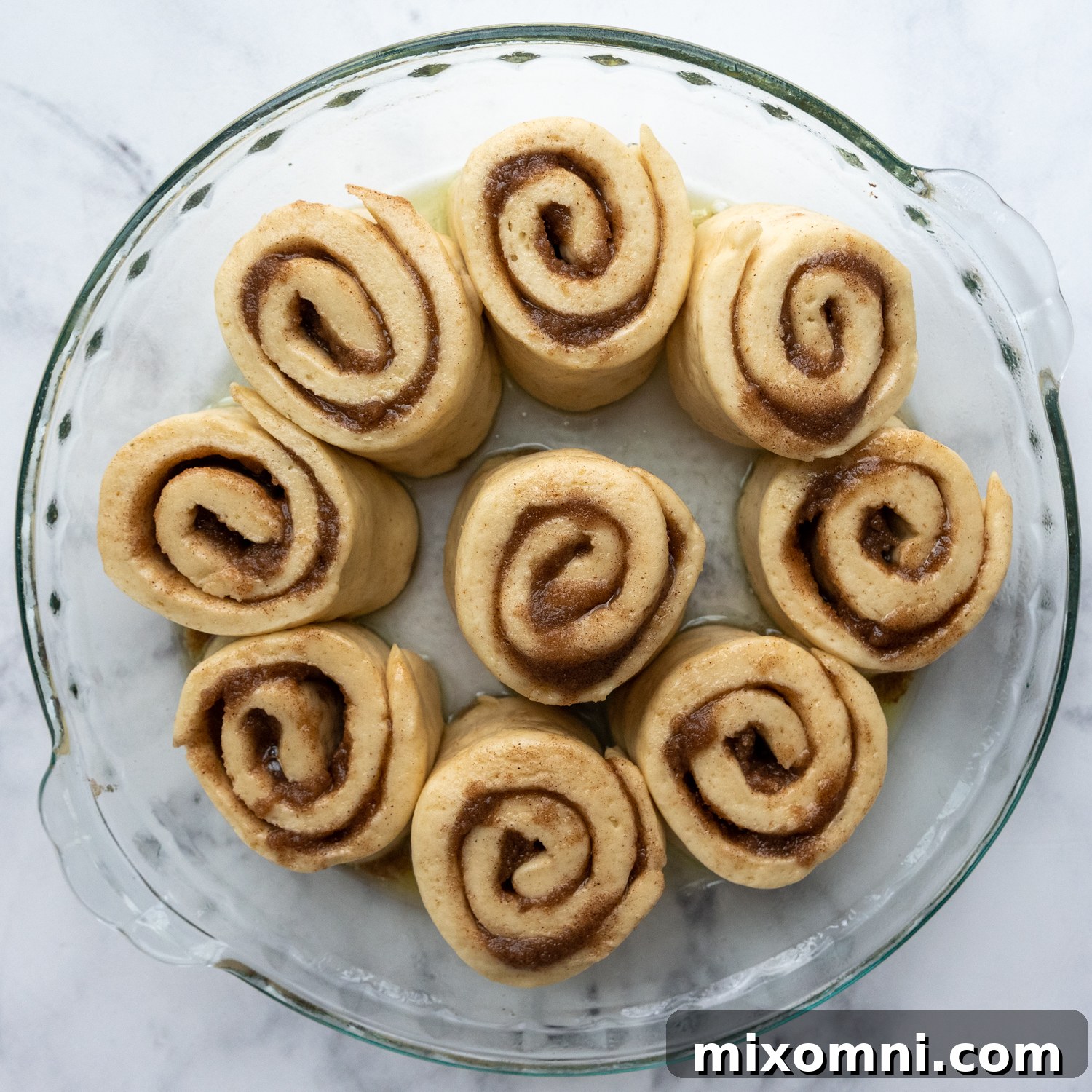 cinnamon buns in a glass baking pan before rising.