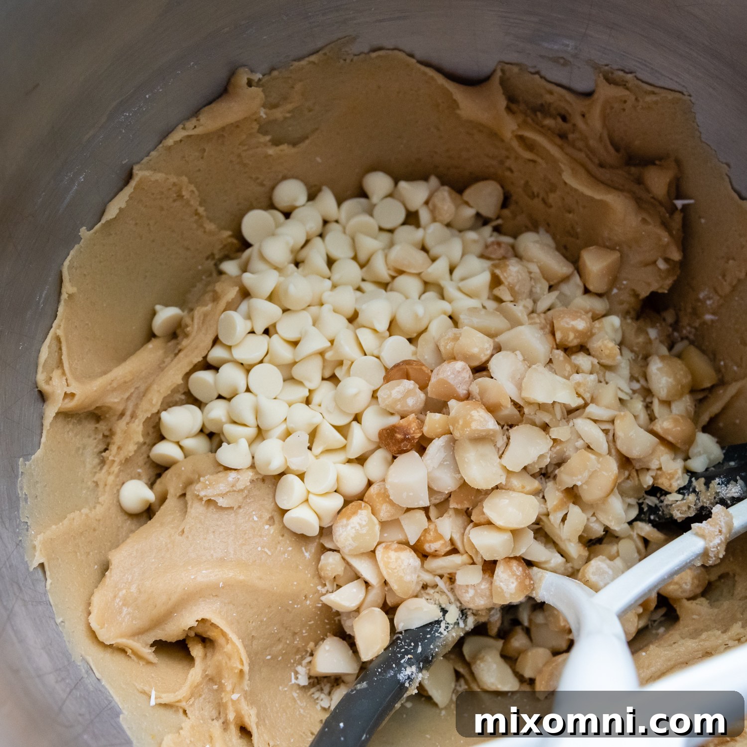 Soft cookie dough generously studded with white chocolate chips and crunchy macadamia nuts, ready for chilling.