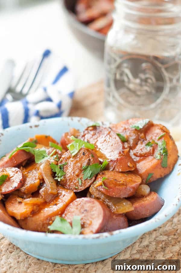 A vibrant blue bowl filled with thick sweet potato and sausage goulash, showcasing chunks of smoked sausage, soft sweet potatoes, and rich red broth. A fork holds up a bite, highlighting the tender ingredients.