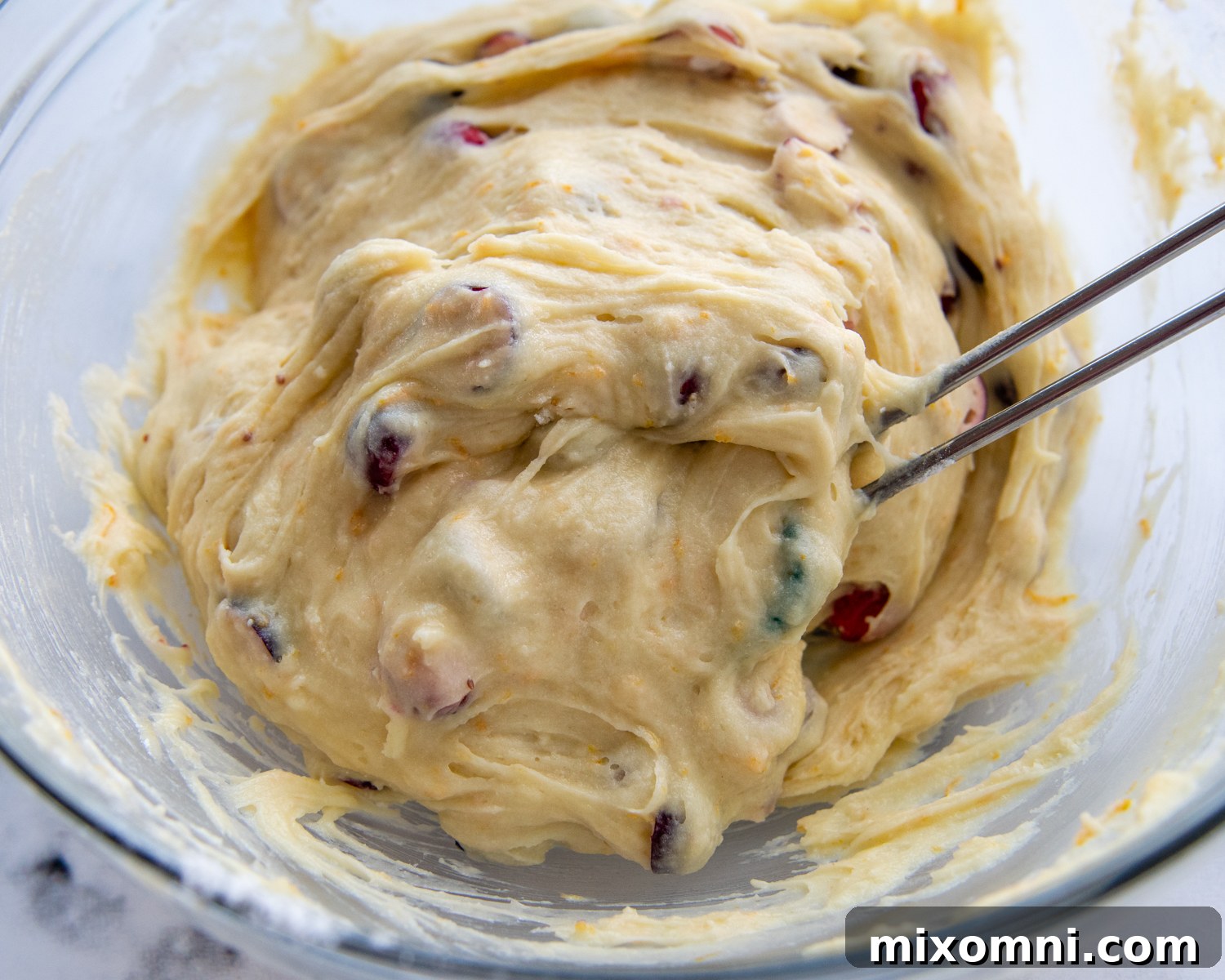 Fully mixed orange cranberry muffin batter, thick and studded with bright red cranberries, ready for baking.