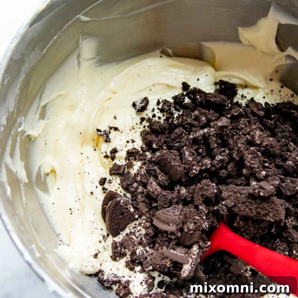 oreos being stirred into a cheesecake mixture