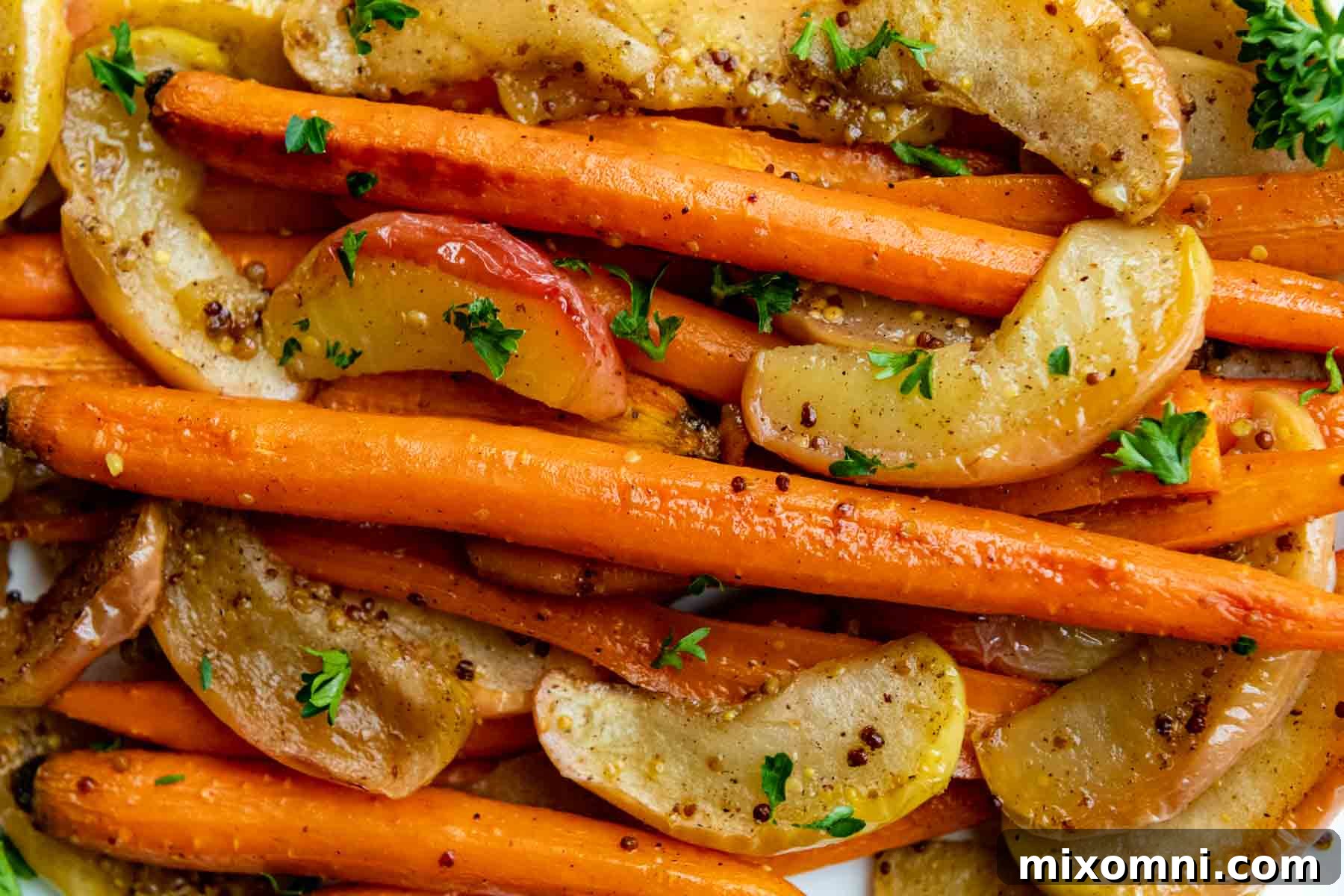 Close-up of roasted carrots and apples, garnished with fresh parsley, highlighting their caramelized texture.